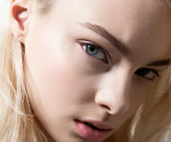 Close-up of a person with tinted, well-groomed eyebrows, highlighting clear skin and light features.