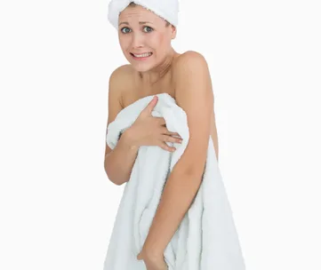 A worried woman wrapped in a towel with a towel on her head.