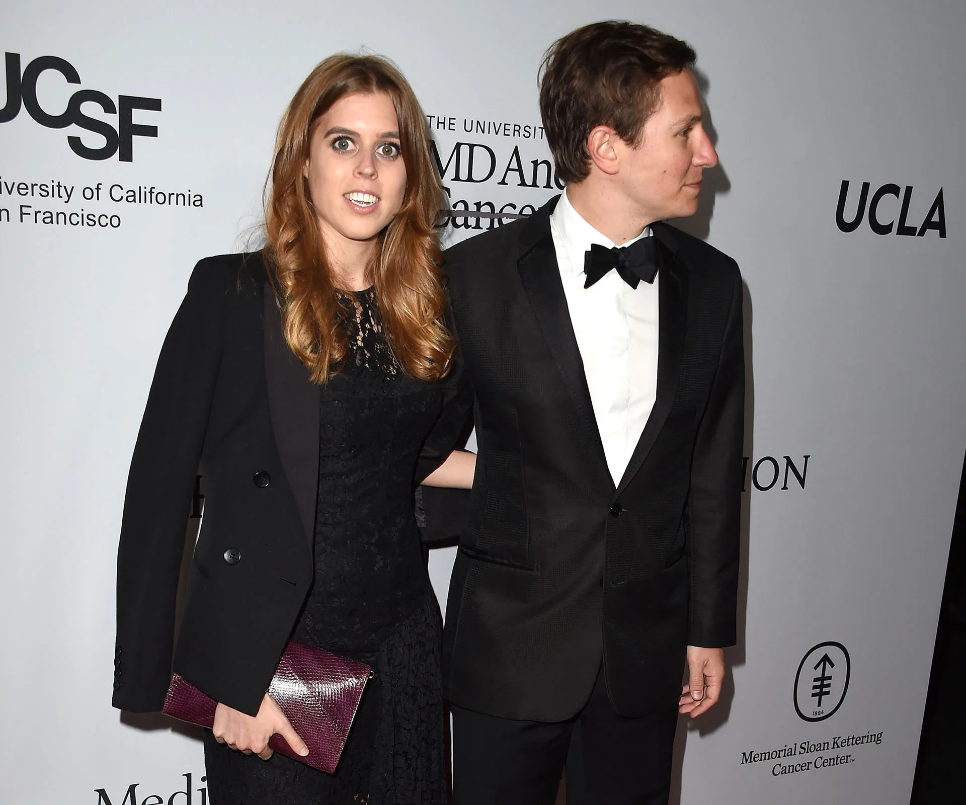 Couple in formal attire at a gala event, woman holding a clutch.