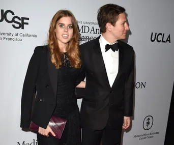 Couple in formal attire at a gala event, woman holding a clutch.