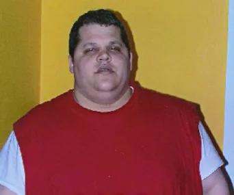 Individual in a red shirt standing in front of a yellow wall.