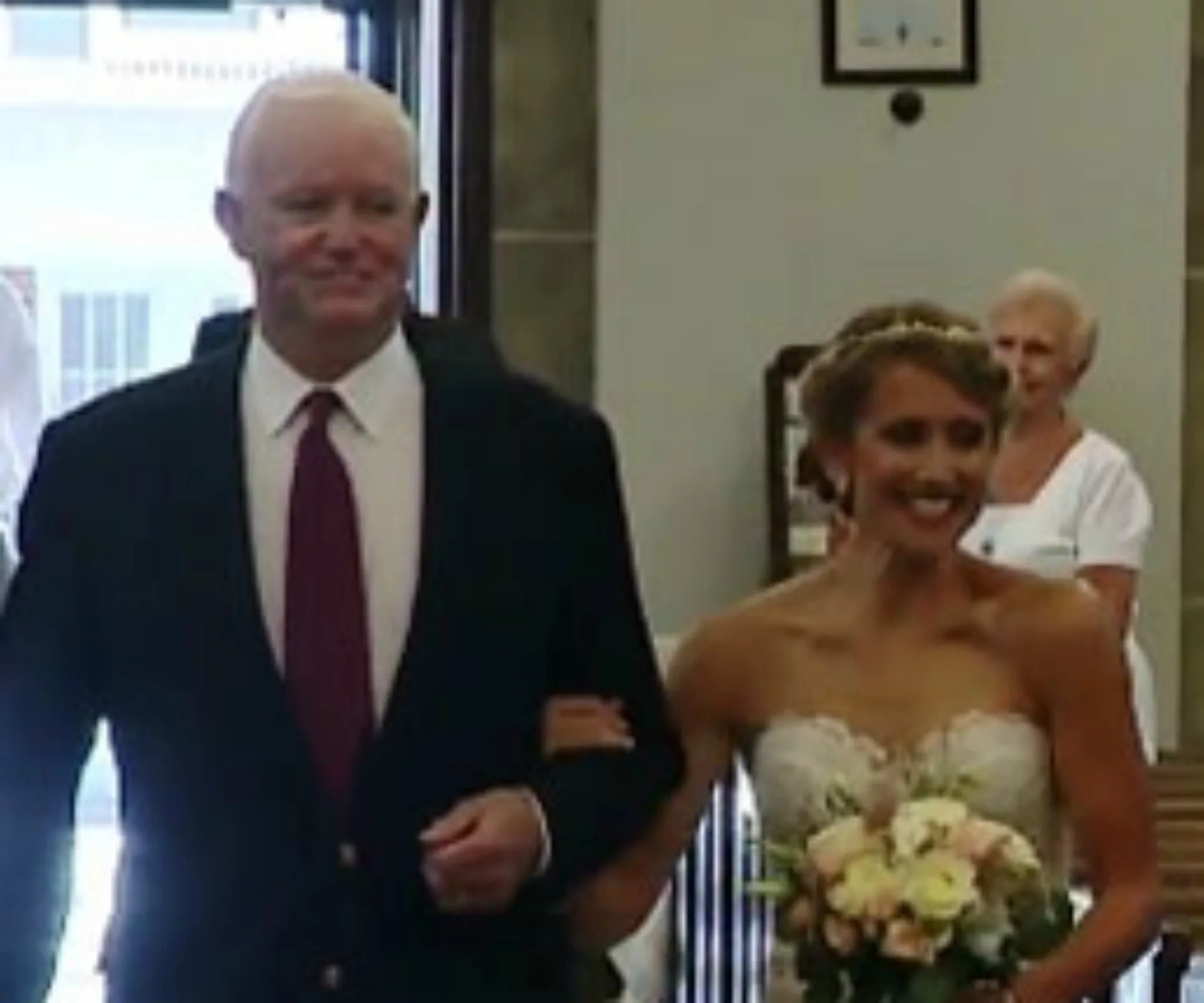 Bride smiles while walking down the aisle arm-in-arm with her father's heart transplant recipient.
