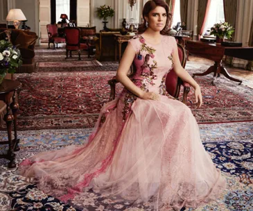 Princess Eugenie in a floral-embellished pink gown, sitting in an elegantly decorated room with ornate carpets.
