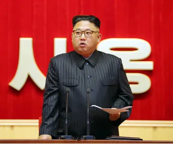 Leader delivering a speech at a podium against a red background.