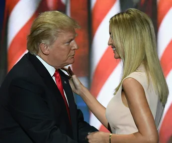 Two individuals in front of the American flag, engaging in conversation on a formal occasion.
