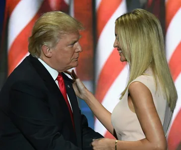 Two individuals in front of the American flag, engaging in conversation on a formal occasion.