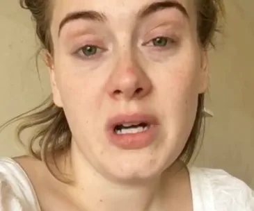 Adele appears emotional in a video expressing regret for canceling her concert.
