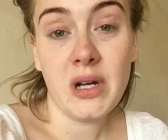 Adele appears emotional in a video expressing regret for canceling her concert.
