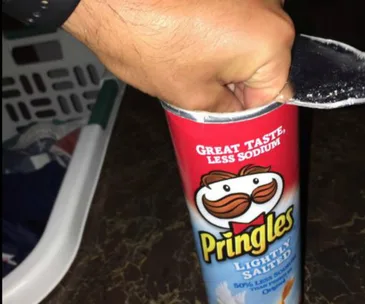 A hand reaches into an open Pringles can, labeled "Lightly Salted, Great Taste, Less Sodium."