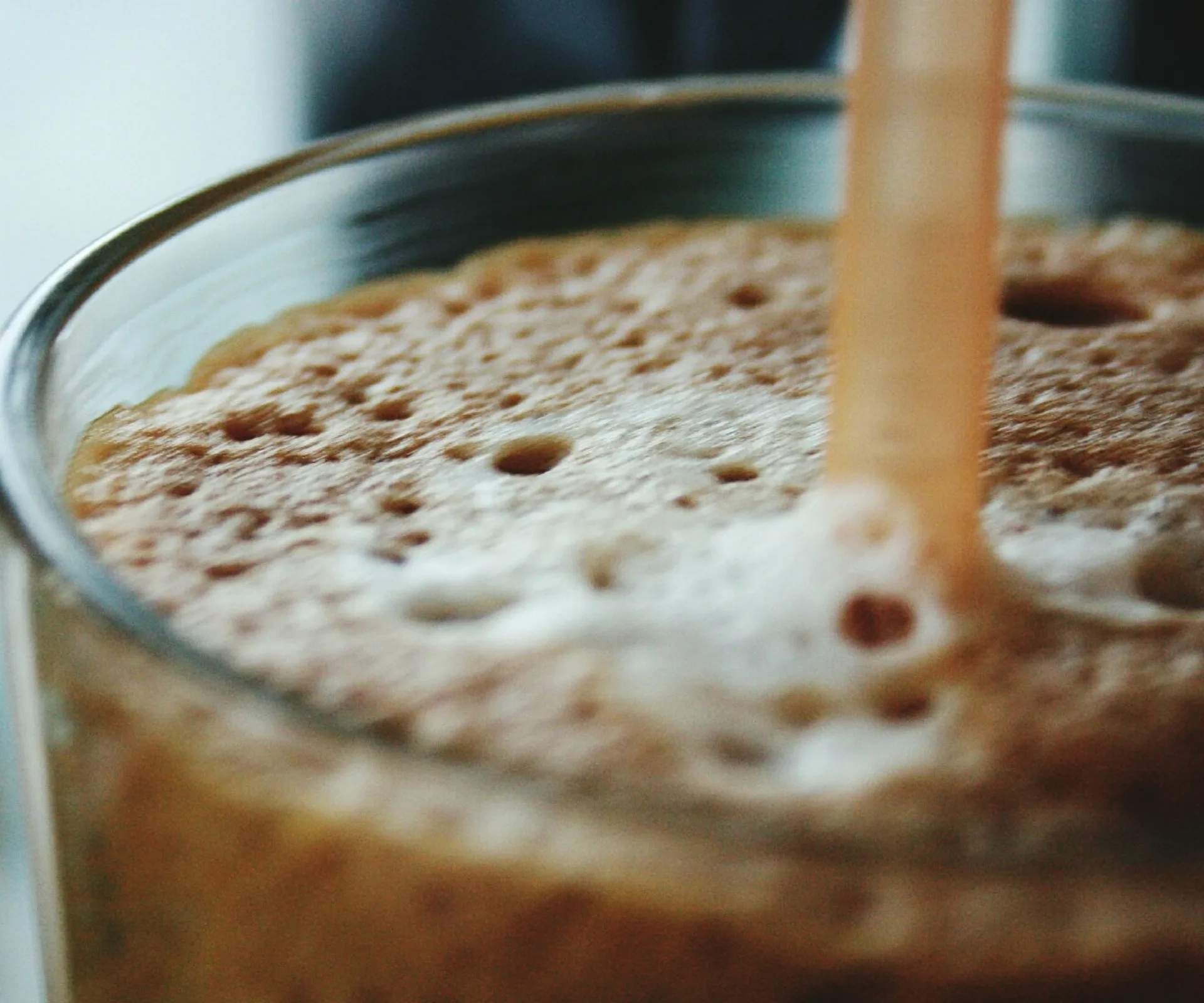Close-up of a fizzy drink surface with bubbles and a straw in a glass.
