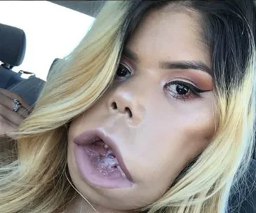 A woman with long blonde hair and makeup sits in a car, displaying confidence and individuality.