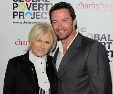 Two people smiling at a charity event, posing in front of a backdrop with logos for Global Poverty Project and Charitybuzz.