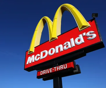 "McDonald's drive-thru sign under clear blue sky."