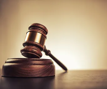 Gavel resting on a sound block against a neutral background, symbolizing justice and law.