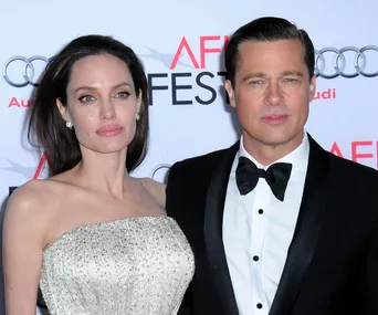 A couple dressed formally on a red carpet at AFI Fest, standing in front of a backdrop with sponsor logos.