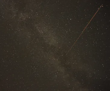 A starry night sky with a bright streak from a meteor across the Milky Way.