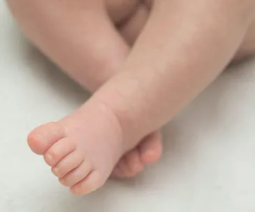 Close-up of a newborn baby's feet resting on a soft surface.