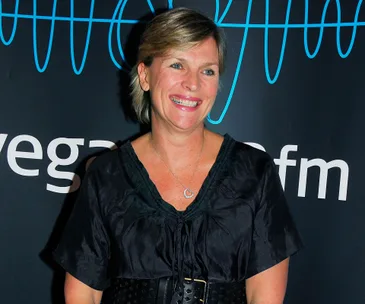 A woman smiling in front of a dark backdrop with "vega" partially visible.