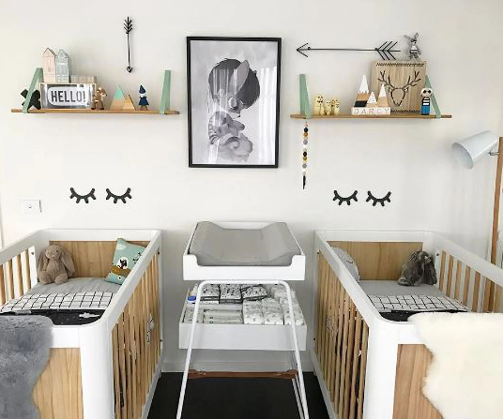 "Modern twins nursery with two cribs, wall art, and decorative shelves in a neutral color scheme."