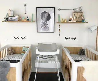 "Modern twins nursery with two cribs, wall art, and decorative shelves in a neutral color scheme."