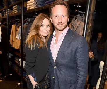 Geri Halliwell poses with a man at a clothing store event, surrounded by shelves of folded clothes.