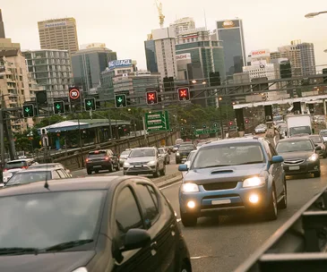 Traffic on a busy highway with city skyscrapers in the background during daytime.