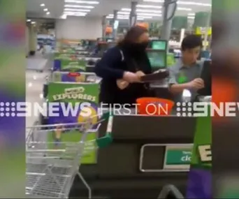 A masked woman wielding a machete at a supermarket checkout counter, captured by 9NEWS.