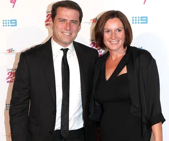 A man and woman smiling and posing together on a red carpet event.