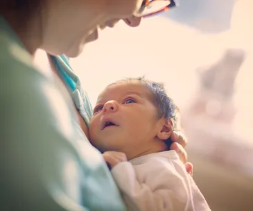 A mother gently cradling her newborn baby close to her chest, both sharing a tender moment.