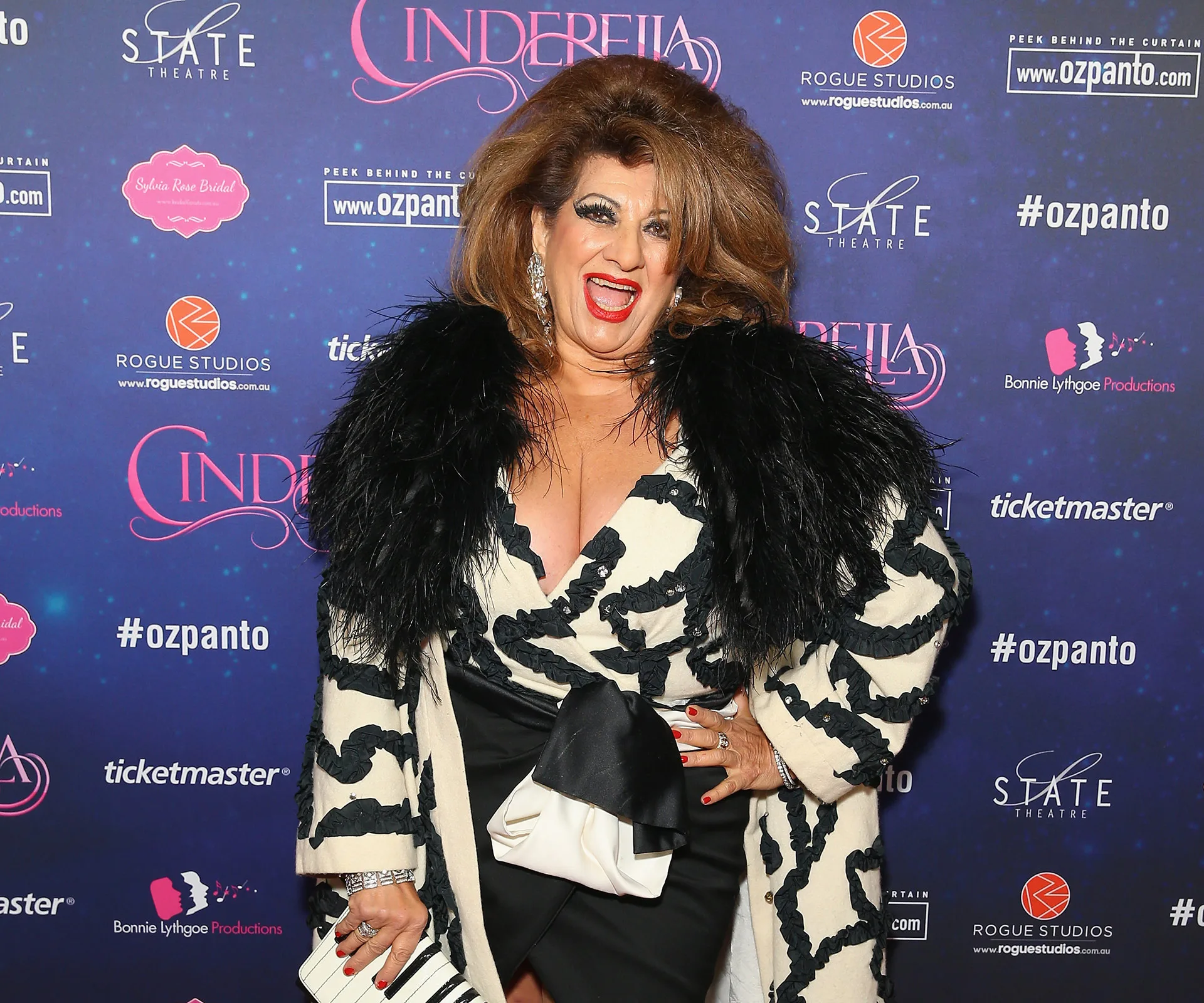 Person in a black and white outfit smiling in front of a "Cinderella" event backdrop.