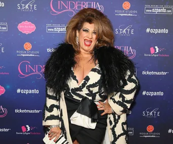 Person in a black and white outfit smiling in front of a "Cinderella" event backdrop.