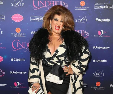Person in a black and white outfit smiling in front of a "Cinderella" event backdrop.