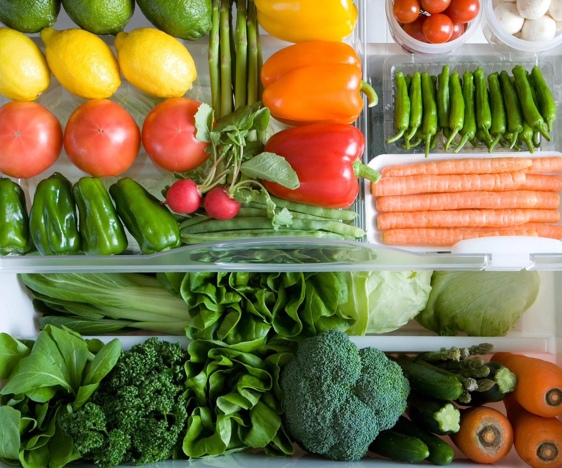 Assorted fresh vegetables and fruits neatly arranged in a refrigerator drawer.