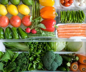 Assorted fresh vegetables and fruits neatly arranged in a refrigerator drawer.