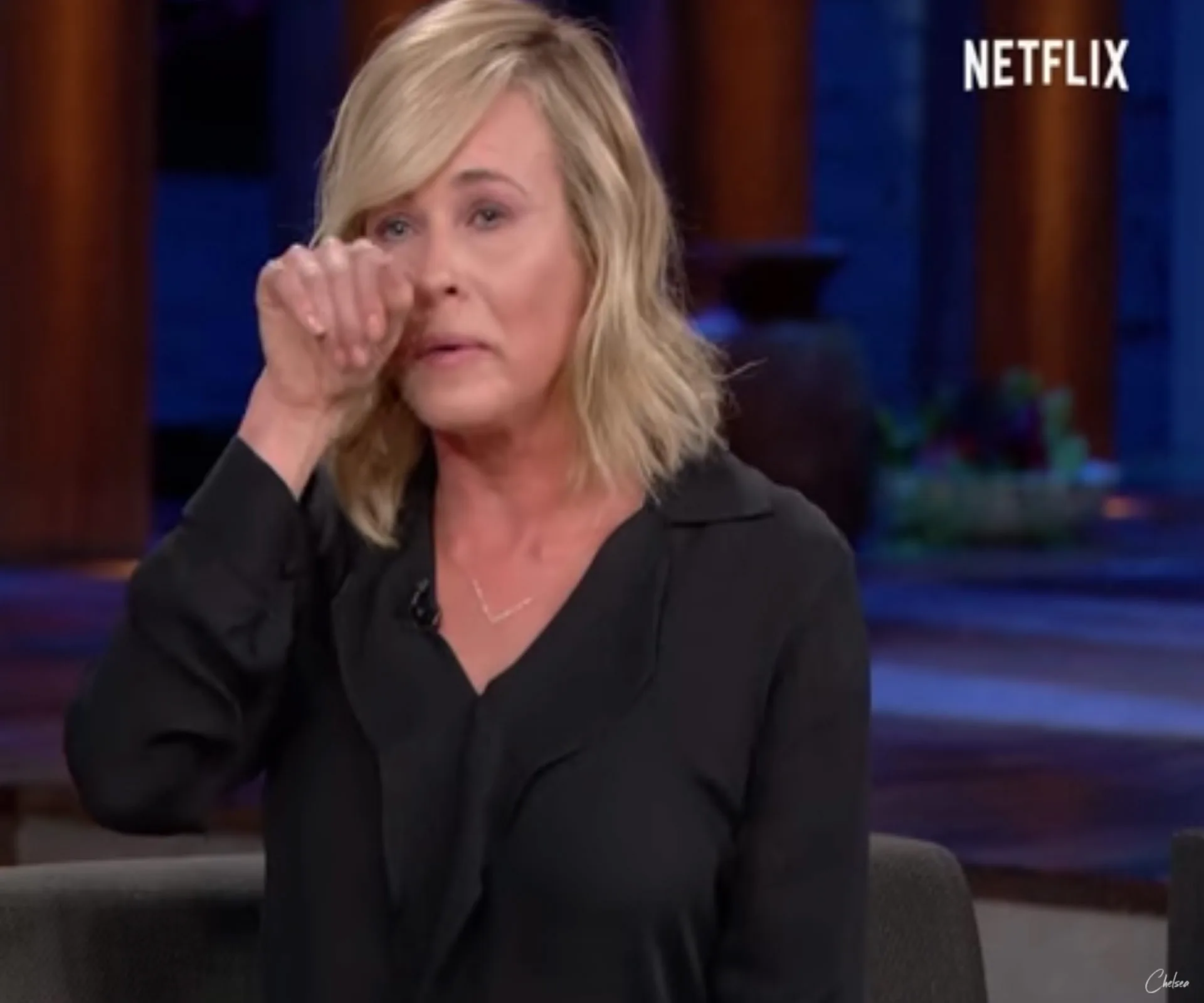 Comedian expressing emotion, wiping tears on a Netflix set.