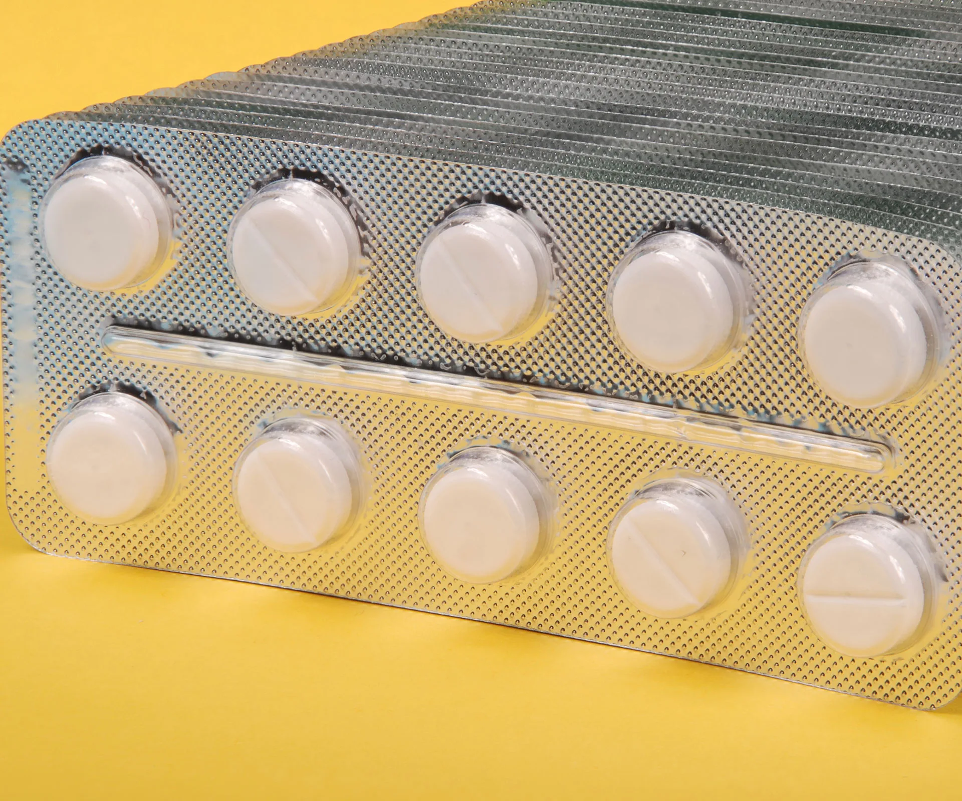 Blister pack of white pills on a yellow background.