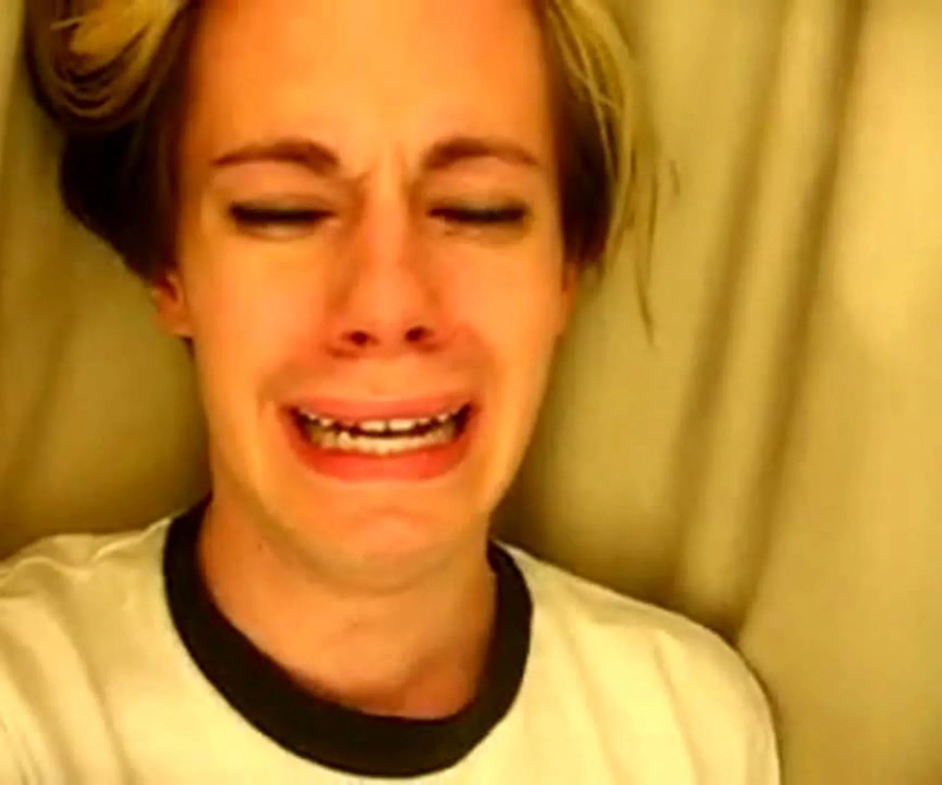 Person with short blonde hair crying, face scrunched up emotionally.