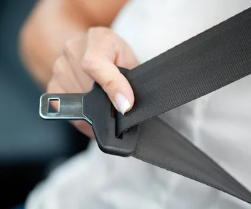 "A hand fastening a black seatbelt in a car, focusing on safety."