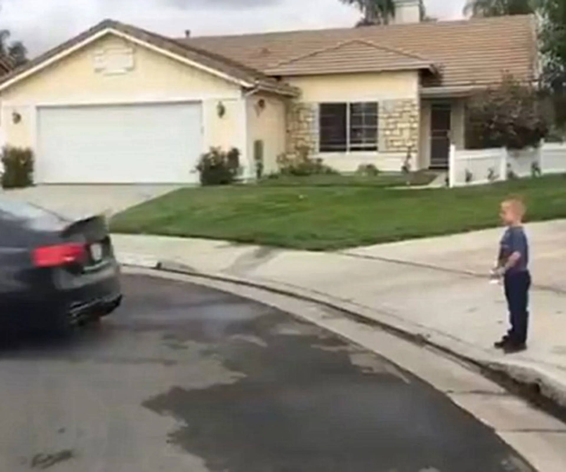 Young boy on sidewalk holding string tied to car pulling his tooth.