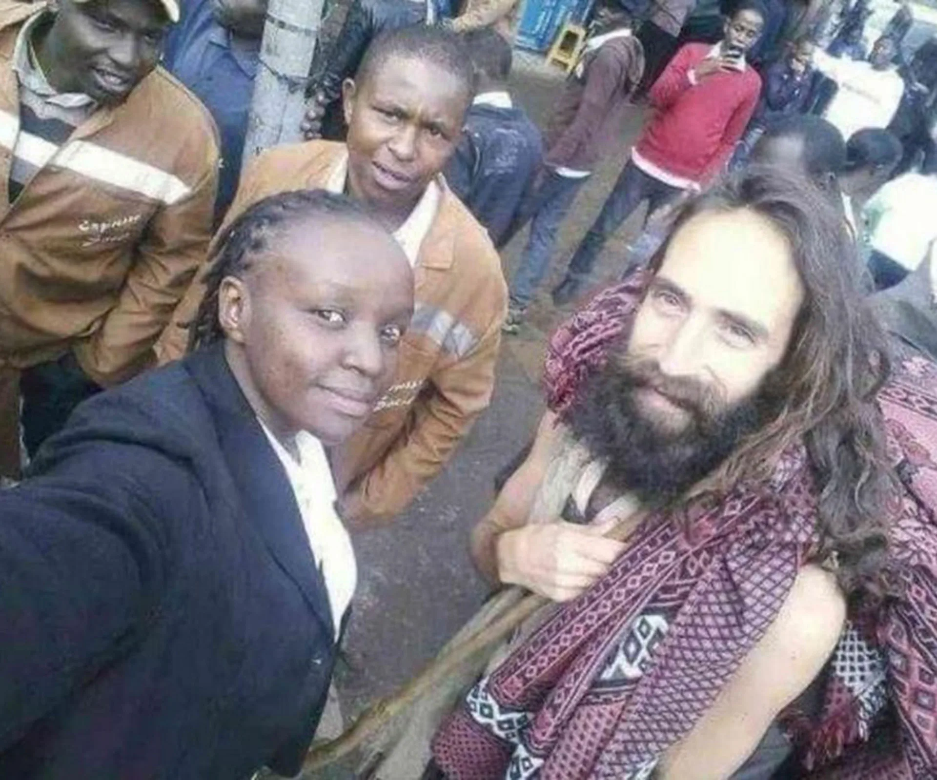 Group selfie with a bearded man in traditional attire, mistaken for Jesus, surrounded by locals on a busy street.
