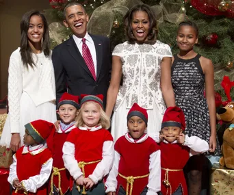 The Obama family poses with children dressed as elves in front of a Christmas tree in the White House.