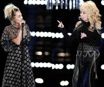 Miley Cyrus and Dolly Parton performing on stage, both wearing black outfits, with microphones in hand.