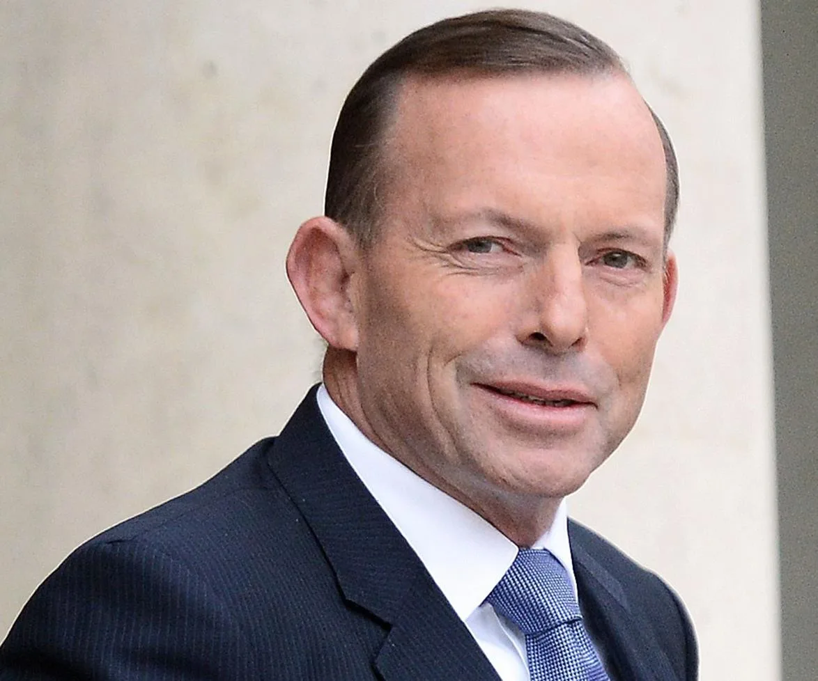 Alt text: "Man in a suit and tie smiling outdoors."