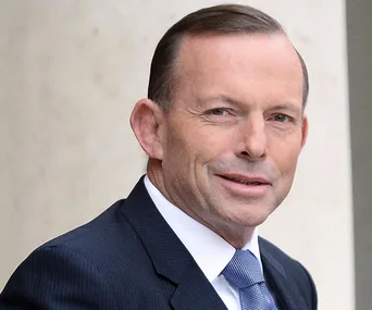 Alt text: "Man in a suit and tie smiling outdoors."