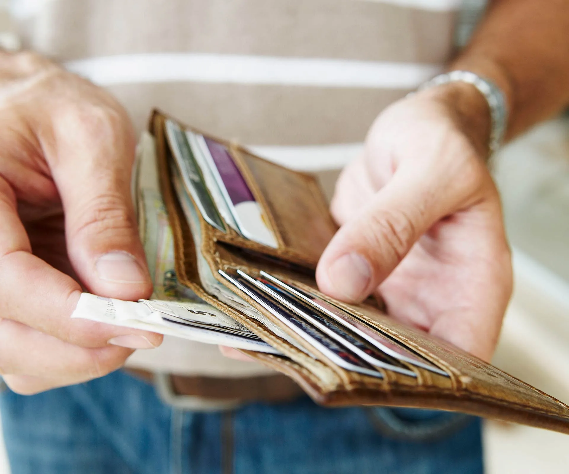 Person holding an open wallet with various cards and cash visible.