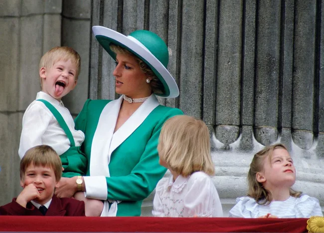 Princess in green holding playful child, balcony scene with three other children.