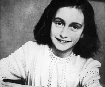A young girl smiling softly, with chin-length dark hair, wearing a light-colored blouse.