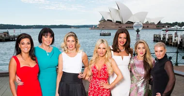 Cast of "The Real Housewives of Sydney" posing in front of Sydney Opera House, dressed elegantly.