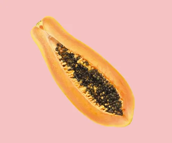 Sliced papaya on a pink background, showing black seeds and orange flesh.