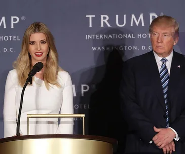 Two individuals stand at podiums against a backdrop with "TRUMP" and "International Hotel" text.